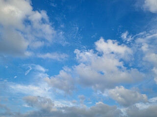 Fototapeta premium Bright blue sky filled with soft scattered white clouds creating peaceful natural atmospheric background scene