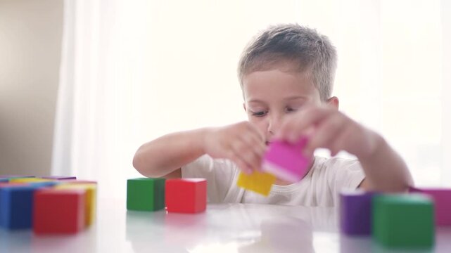 A child plays with blocks and toys in a kindergarten. Happy family kid dream concept. A child plays with blocks. The child plays with blocks and collects toys on the table as a way of life.