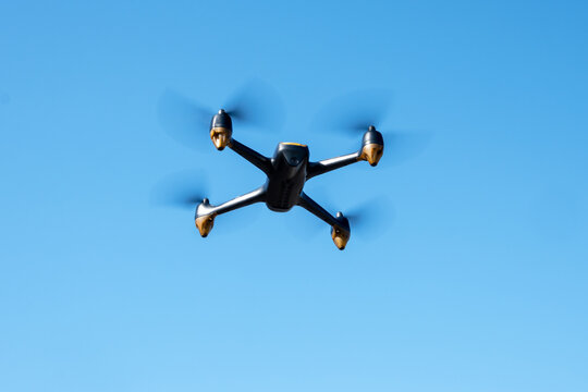 Industrial drone flying in clear blue sky. Modern technology for game, delivery or work.