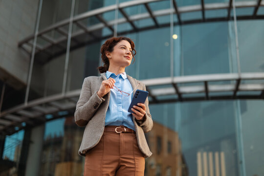 Businesswoman holding smartphone with confident gaze reflecting determination