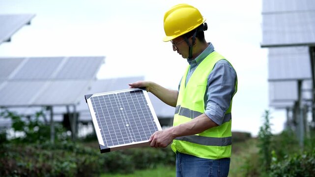 Engineer holding a solar panel while inspecting a photovoltaic power station outdoors