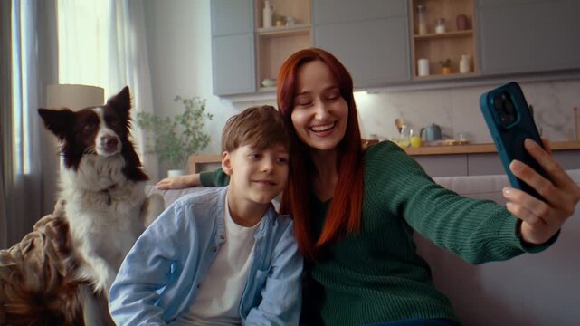 Woman takes selfie with smiling boy and dog sitting nearby