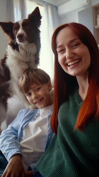 Woman and boy talk on video call with dog on sofa at home