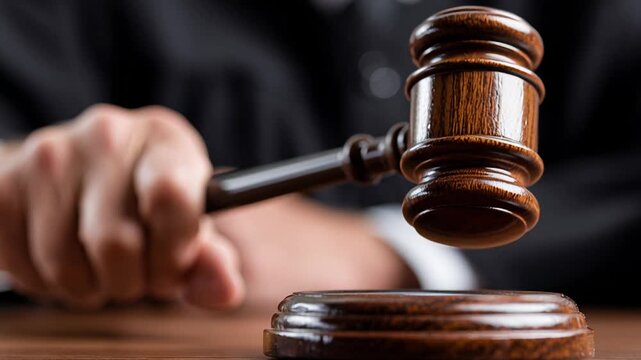 Judge gavel striking wooden block, caucasian judge in black robe delivering decisive verdict in courtroom; close-up on hand, polished mallet, echoing authority,
