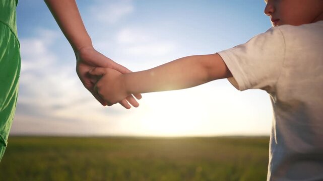 Mom and son join hands in the garden park. Concept of love in family of woman mother to son. Close-up of family hands. Close-up of mother and son joining forces in the park lifestyle of.