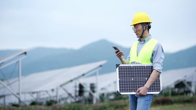 Engineer holding solar panel while checking data on smartphone at photovoltaic site