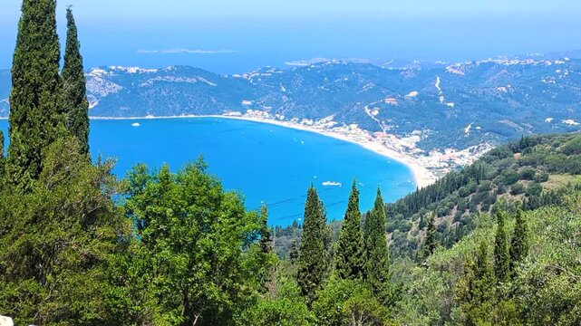 Beautiful landscape of Agios Georgios bay with wide beach, azure waters of Ionian Sea, green trees and sunny blue sky. Corfu or Kerkyra island. Greece.