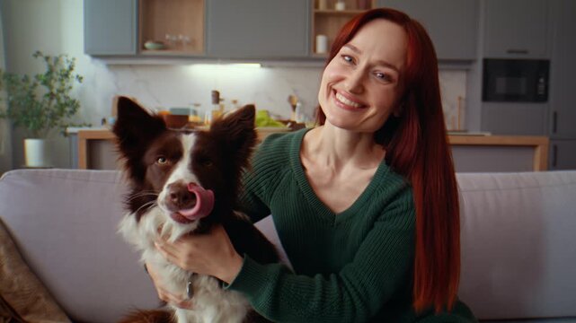 Woman hugs dog smiling confidently on cozy sofa at home