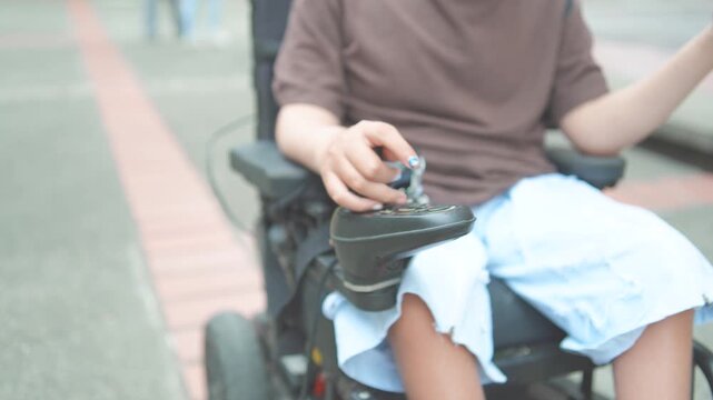 Close-Up of Male Hand with Fingernail Polish Operating Electric Wheelchair Joystick Control Outdoors