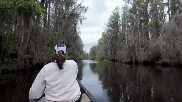  footage of a woman paddling a canoe through the Okefenokee Swamp in Georgia, USA.
