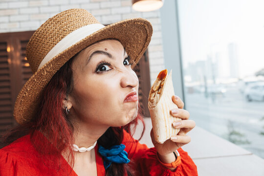 Woman making a suspicious, disgusted face while smelling a chicken wrap or burrito with sauce, reacting to an unpleasant odor and questioning food freshness