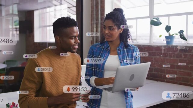Woman scrolling laptop, man pointing, floating badges rising between them showing business metrics