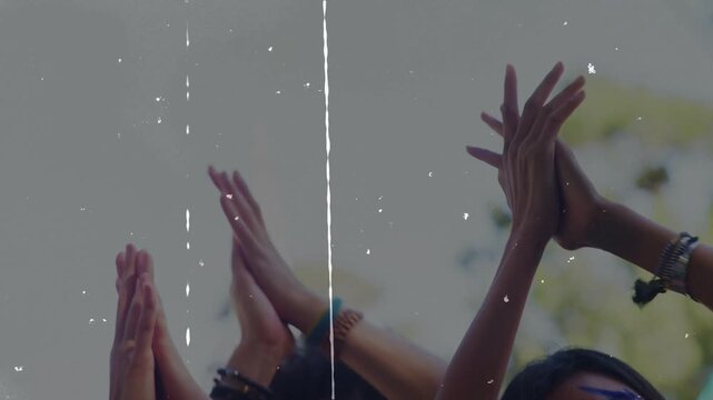 Group at music festival moving to beat, raising and clapping, becoming film-grain silhouettes