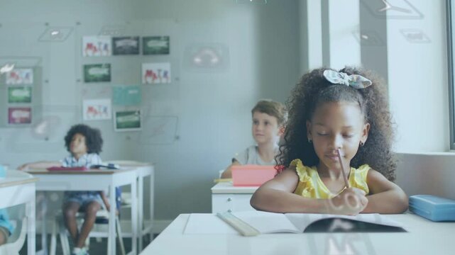 Girl writing in classroom at desk as digital icons drifting around face, pausing for education