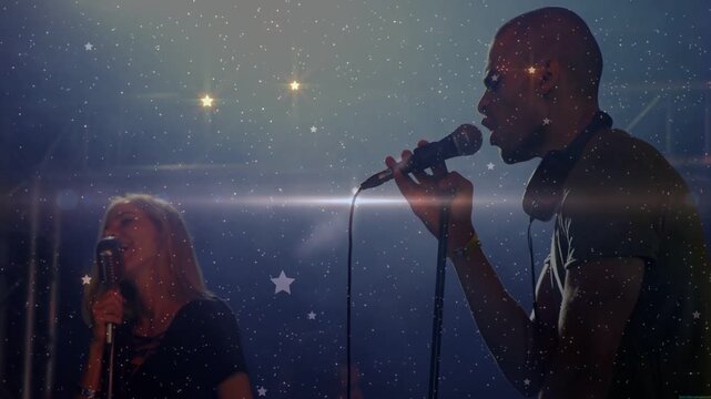 Male singer singing and gesturing on dim stage, backlight causing sparkles, music duet for audience