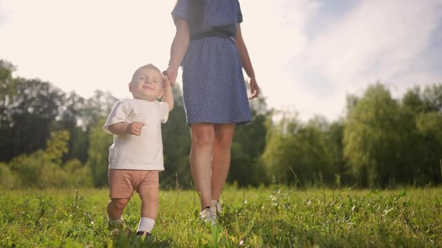 Mom and baby taking the first steps. Child walk step family concept. Mom and baby on steps in the park. Mom and baby taking first steps lifestyle in the. park. family motherhood concept.