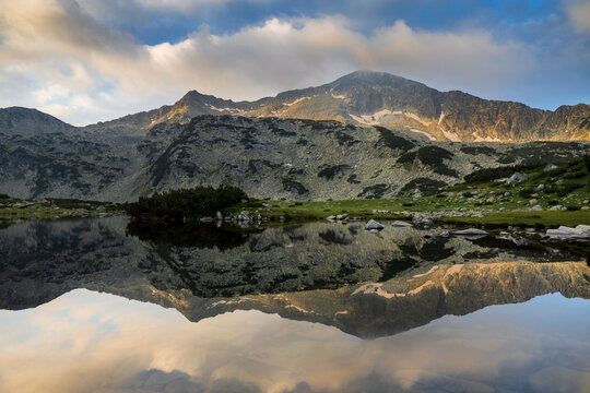 Reflection of rocky peak in the calm water in Pirin mountain. National park in Bulgaria.