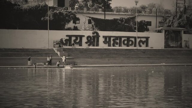 Sepia Tone View of Mahakal Ghat with &ldquo;Jai Shri Mahakal&rdquo; Sign and Devotees at Riverbank Ujjain