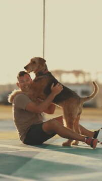 Happy man playing with airedale terrier dog outdoors
