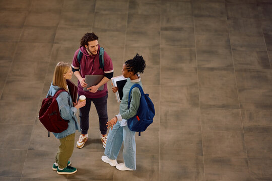 Adobe view of multiracial group of university students talking in hallway.