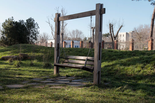 Wooden bench swing standing idle in a grassy outdoor park area