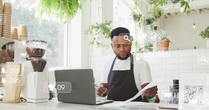 Animation of social media icons and numbers over african american barman using laptop