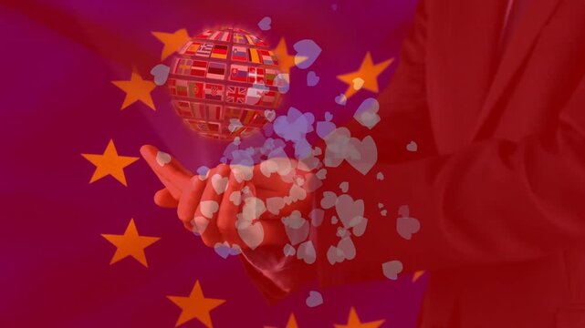 Presenting hand in dark suit holding flag globe appearing above palm on star field, hearts forming