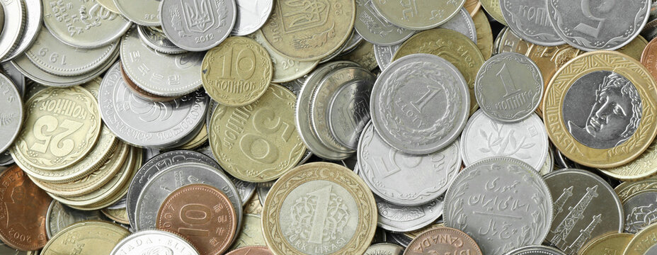 Pile of global currencies, various coin types visible up close. Different nations money together