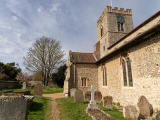 Fototapeta premium Quaint rural village St Marys Church Westgate, Burnham Market. Quintessential Stone building English village church and cemetery on a summers afternoon.