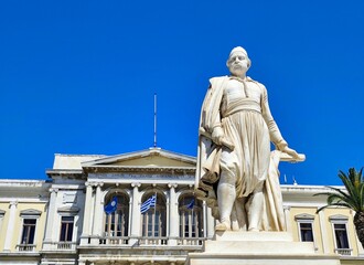 Obraz premium Photo of the marble statue of Admiral Andreas Miaoulis in Miaouli square on the island of Syros, set before the neoclassical Town Hall designed by Ernst Ziller.
