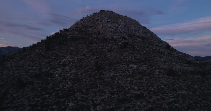 Rocky Mountain Summit At Dusk With Purple Twilight Sky, Granite Ridgeline And Scattered Boulders, Drone Aerial Revealing Remote Wilderness, Moody Cinematic Lighting,