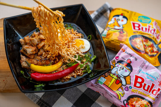 Korean Ramen Buldak noodles with egg, chili and chicken in bowl lifted chopsticks, tasty Authentic Asian street food, Homemade meal, global trend popular food product, Frankfurt - September 30, 2025