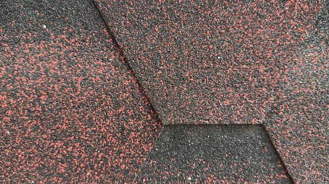 Close-up red hexagonal shingles texture, flexible asphalt roofing with coarse granules, overlapping pattern with subtle weathering.