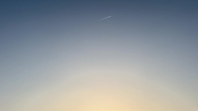 Minimalist view of a clear blue sky with an airplane leaving a faint contrail above a residential area in China.