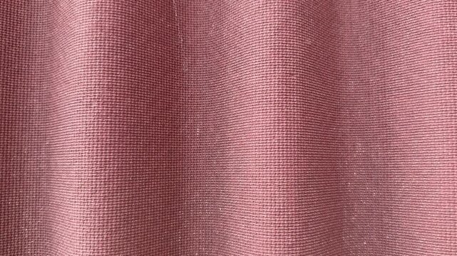 Close-up ondulin roofing tile texture showcasing pink corrugated waves and fibrous granulated surface, macro architectural study.