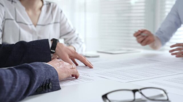 Business people discussing contract details during an important corporate meeting, partners reviewing legal documents with an attorney, collaborating on an agreement