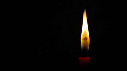 Fototapeta premium Photo of a solitary candle flame burning against a deep, solid black background, symbolizing hope, remembrance, prayer, and peaceful atmosphere.
