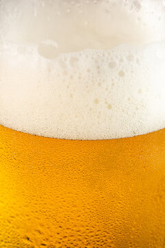 Closeup of a glass of beer with foam and water droplets 
