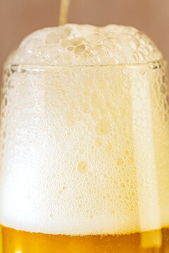 Closeup of a glass of beer with foam and water droplets 