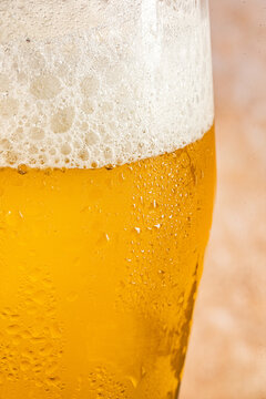 Closeup of a glass of beer with foam and water droplets 