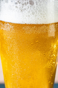Closeup of a glass of beer with foam and water droplets 