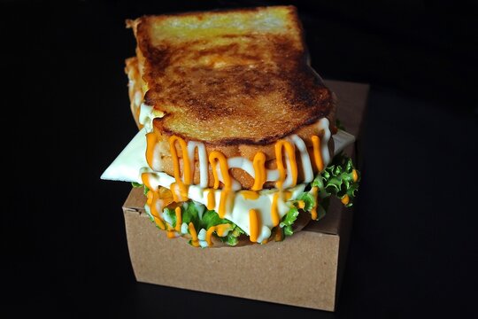 Grilled Toast Sandwich with Melted Cheese and Creamy Sauce on Black Background.
