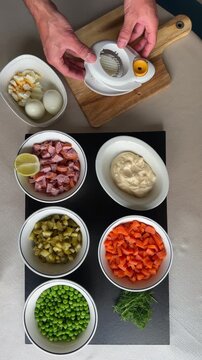 High angle view of cook putting egg in a slicer for classic Olivier Ruska Salad