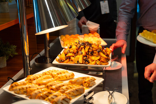 Person serving roasted potatoes from a buffet station