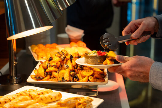 Person serving roasted potatoes from a buffet station