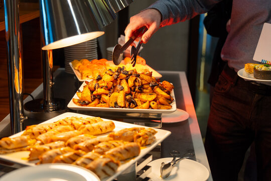 Person serving roasted potatoes from a buffet station