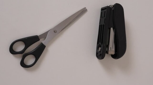 Stapler and scissors on desk, office supplies concept, minimal workspace setup, tools for document fastening and cutting, clean business environment.
