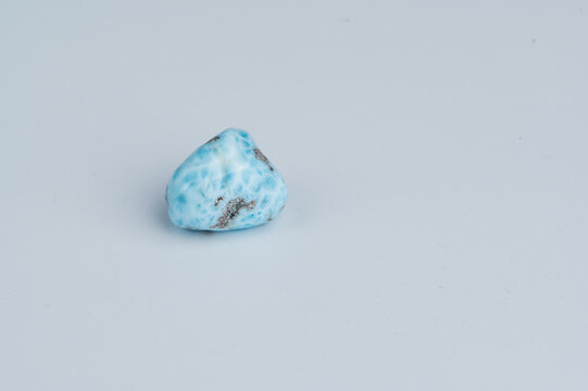 A blue and white Larimar gemstone sits on a flat, light surface.