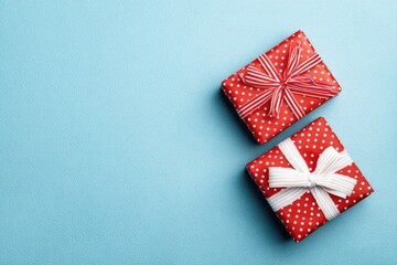 Obraz premium Two red polka dot gifts with ribbons on blue textured background
