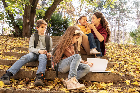 Energetic teacher leads a small, diverse group of preschoolers on an outdoor nature exploration, pointing out interesting details of the local flora and fauna.